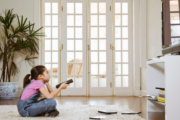 little girl watching television at home alone