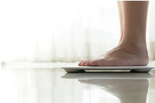 woman weighing herself on a scale trying to lose weight