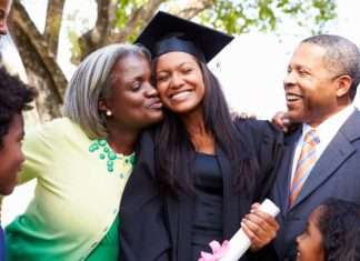 5 Surprises You Can Give Your Kids at Their Graduation A young female in a black graduation gown and hat is being embraced by two parents in formal attire. Two children look on.
