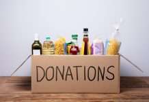 5 Helpful Ways To Serve Your Community This Winter A cardboard box with "DONATIONS" written in black marker on the side. The box is filled with pasta, olive oil, and rice.